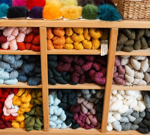 Shelves filled with colorful yarn balls in a store setting.